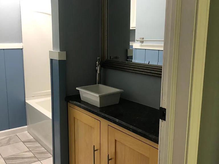 Custom poplar cabinet with vessel sink, porcelain tile, large tub with curved shower curtain rod.