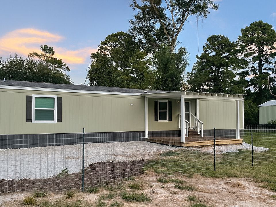 Mobile home fenced off, gravel driveway, and patio deck