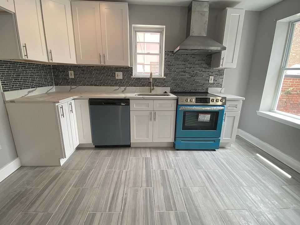Large sunny modern white kitchen, quartz countertop, porcelain tile floor, stainless steel appliance