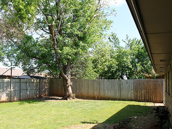 Large, shaded backyard with privacy fence
