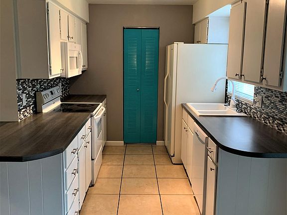 Galley style kitchen with range, microwave, dishwasher and refrigerator.