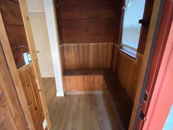 Cozy enclosed entry nook with built-in seating. Ideal for shoes, coats, or simply a quiet spot to unwind.