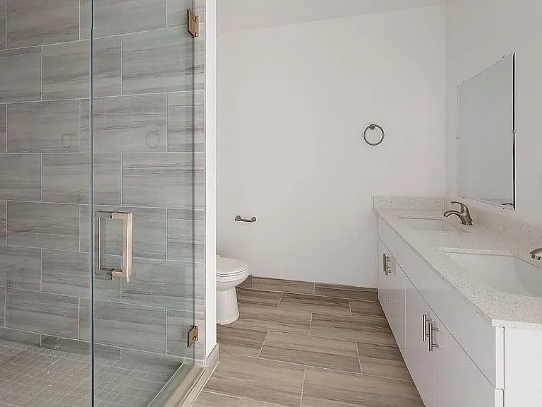 Elegant modern bathroom featuring a sleek glass shower and a double sink with polished countertops.