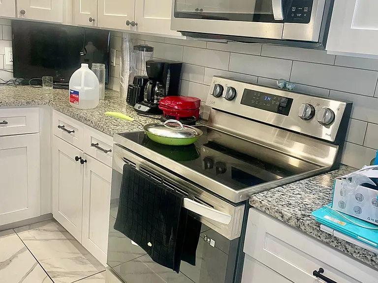 Updated kitchen with granite counters, subway-tile backsplash, and stainless steel range with over-the-range microwave.