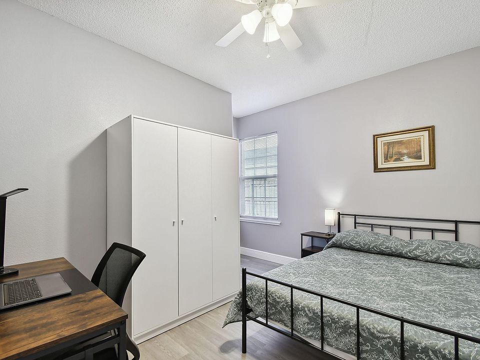 Full size cozy bed, with end table, light, office desk, chair and light as well as storage container under the bed.