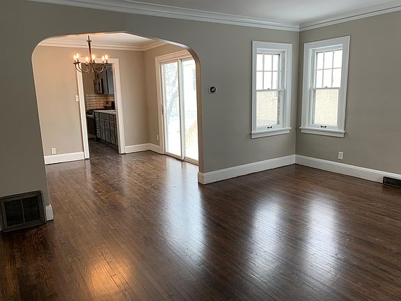 Open concept living room and dining room with original crown molding and wood burning fireplace