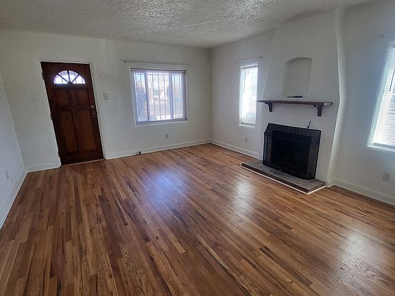 Living room, showing beautifully refinished hardwood floor and fireplace.