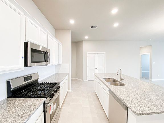Kitchen has white cabinets, stainless steel appliances and 5-burner gas range