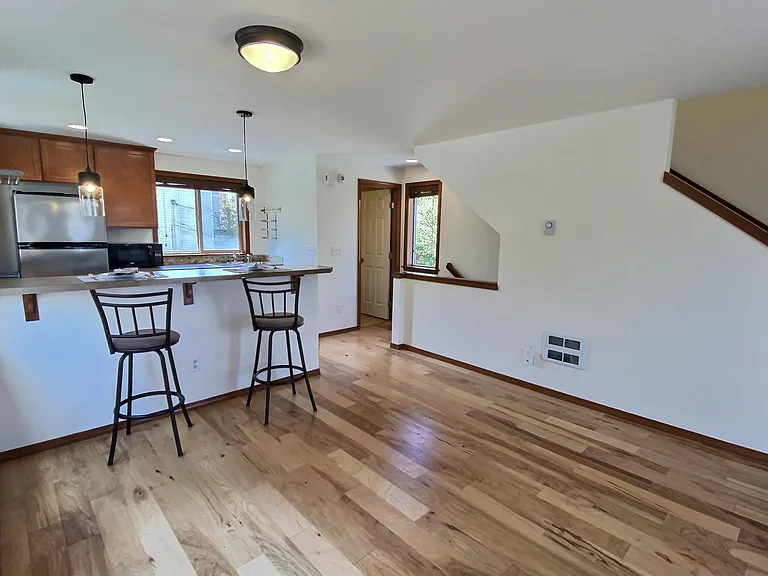 2nd Floor _ Open-concept living area featuring sleek hardwood flooring, a cozy tiled fireplace, a kitchen with stainless steel appliances and a premium slide-in electric range, plus a convenient half bathroom.