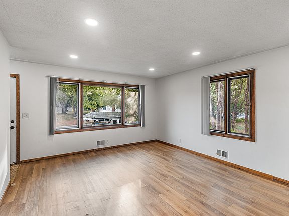 Main Level Living Room: Bright and spacious living room with large windows, dimmable recessed lighting, and beautiful LVP flooring, perfect for quality family time or hosting fun gatherings.