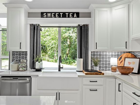 Farmhouse sink beautiful white cabinetry and light grey black and white backsplash.