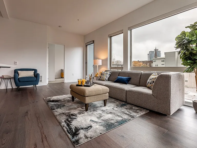 Window-Lit Lounge Area with Couch, Ottoman, and Decor Plant