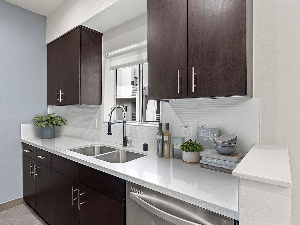 White tile kitchen with granite countertop and stainless steel fridge, oven, and fixtures.