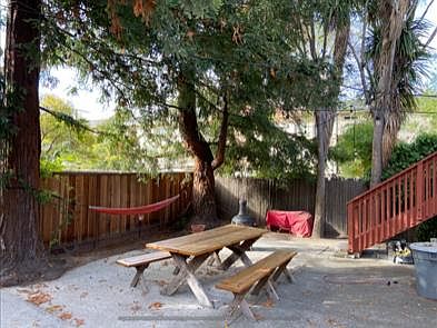 Outdoor sitting area under 2 large redwood trees.