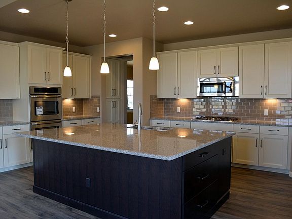 Gourmet kitchen w. staggered height 42" cabinets, undercabinet lighting, stainless steel appliances, slab granite, soft close drawers/doors, and backsplash.