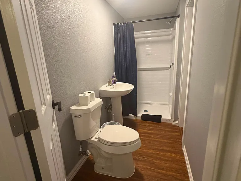 Functional bathroom with a tub/shower combo, pedestal sink, and easy-care flooring for simple daily routines.