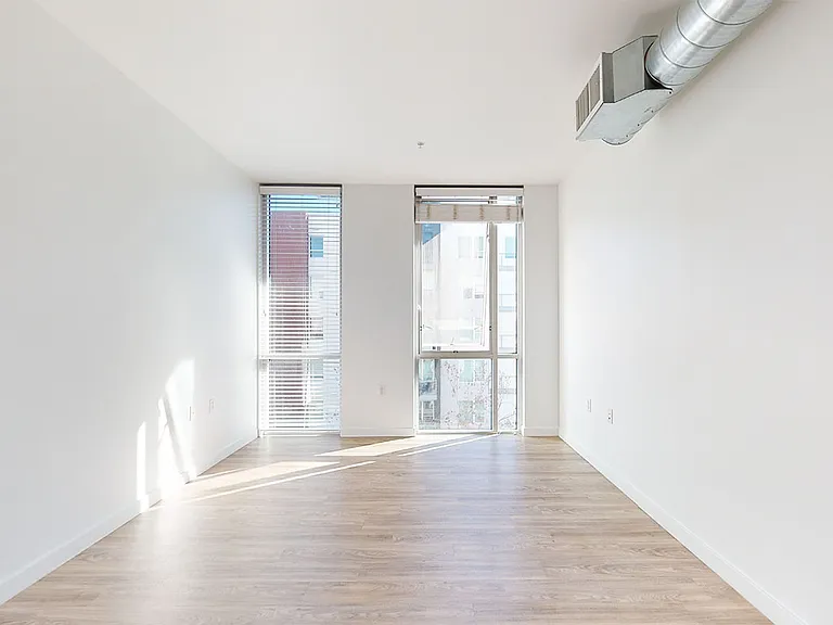 Apartment living room with wood-style flooring and floor-to-ceiling windows.