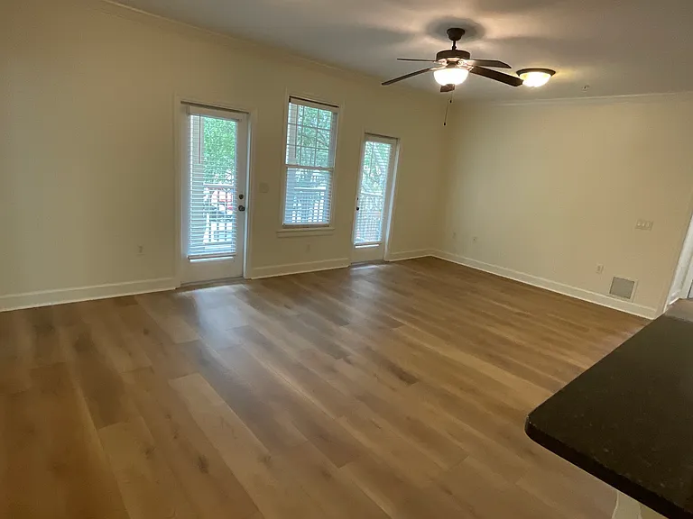 Large open concept kitchen, dining, living areas with ceiling fan, crown moldings, doors to balcony