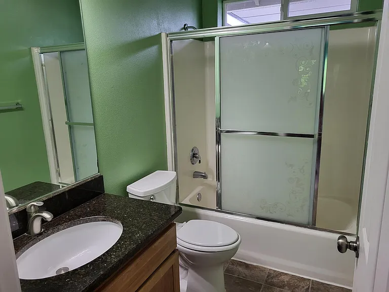 lovely hall bath with undermount granite sink and shower with door.