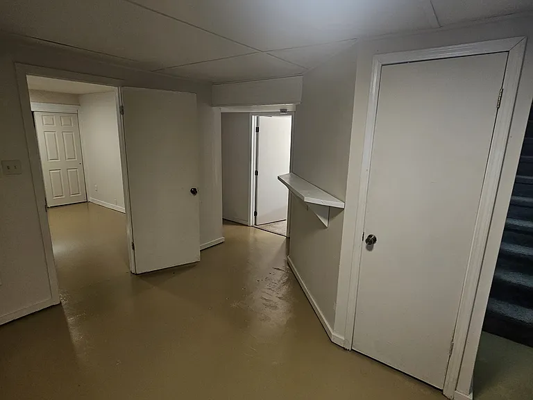 Door with the light on is the bathroom. Floors downstairs are painted cement.
