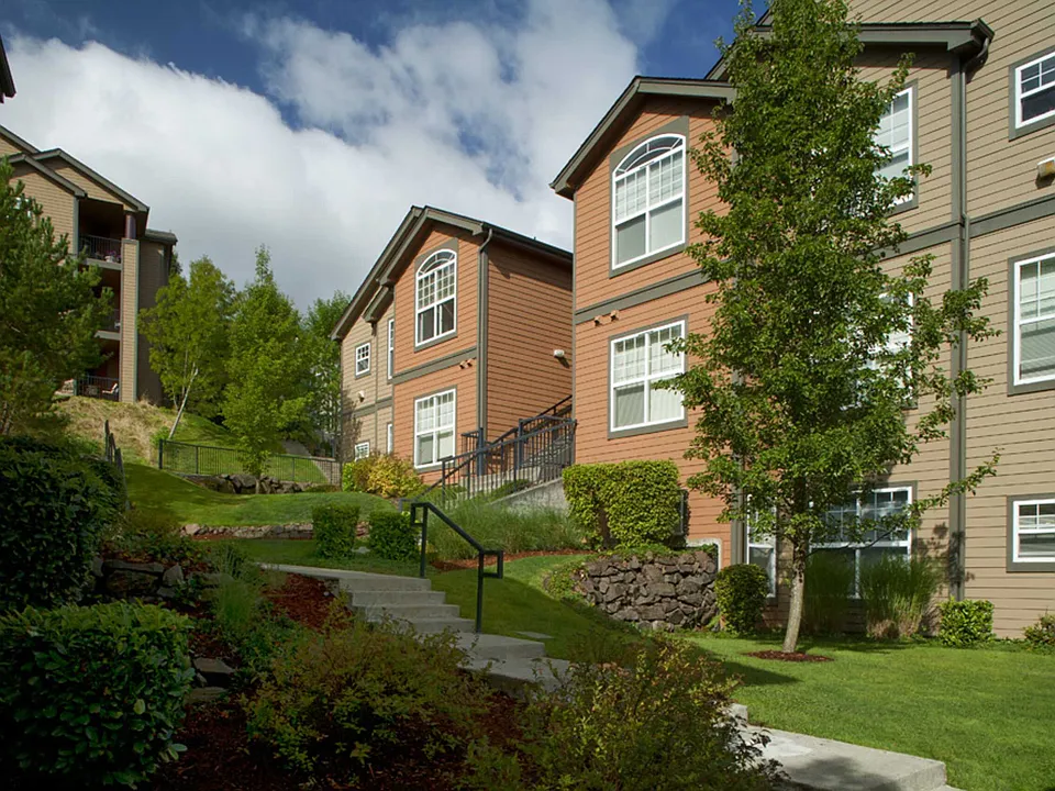 Evergreens and landscaped grounds frame the apartment buildings throughout the community.