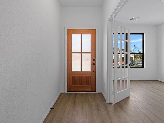 Inviting foyer featuring gorgeous flooring and a beautiful stained door.