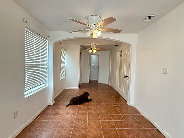 2nd BR "Flex Suite" - photo taken standing at front of bedroom looking back: bathroom door straight ahead, two large windows with blinds on L, and bedroom door on R leading out to living/dining area.