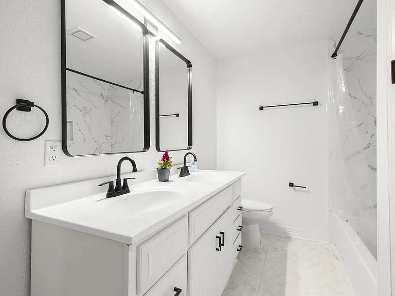 Shared bathroom with tub, double vanity, double mirror.