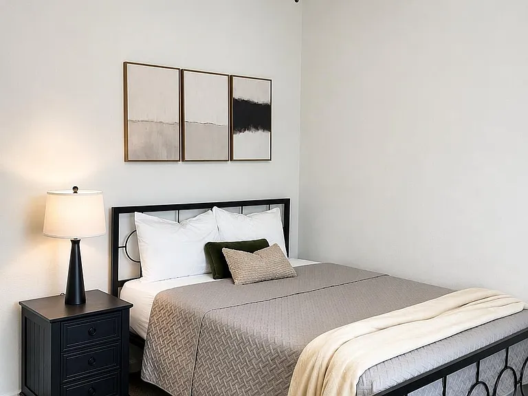 Furnished bedroom with a full bed, nightstand, and ceiling fan, offering a comfortable layout and neutral finishes.