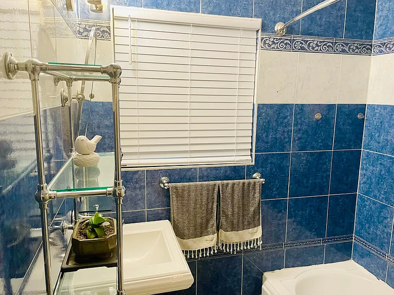 Full bathroom with bathtub and glass shelves. New blinds throughout the house.
