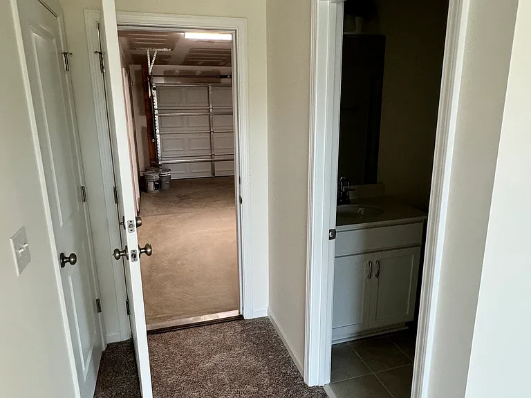 Guest bedroom with a door directly to the garage. Door on the left is a small closet.