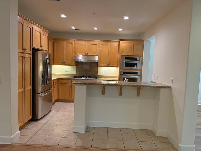 Gourmet kitchen is equipped with stainless steel appliances and soft-close cabinetry and granite countertop with a breakfast bar.
