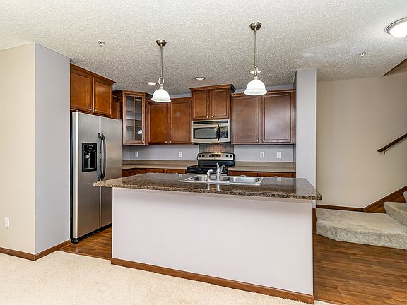 Center island with granite and built-in sink, recessed lights and pendant lighting.