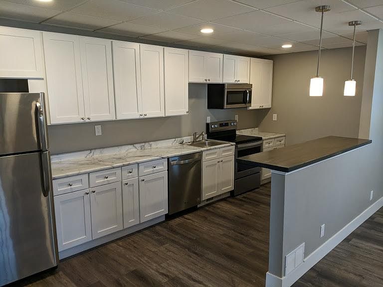 Large kitchen with butcher block island. Stainless steel appliances including dishwasher and microwave.