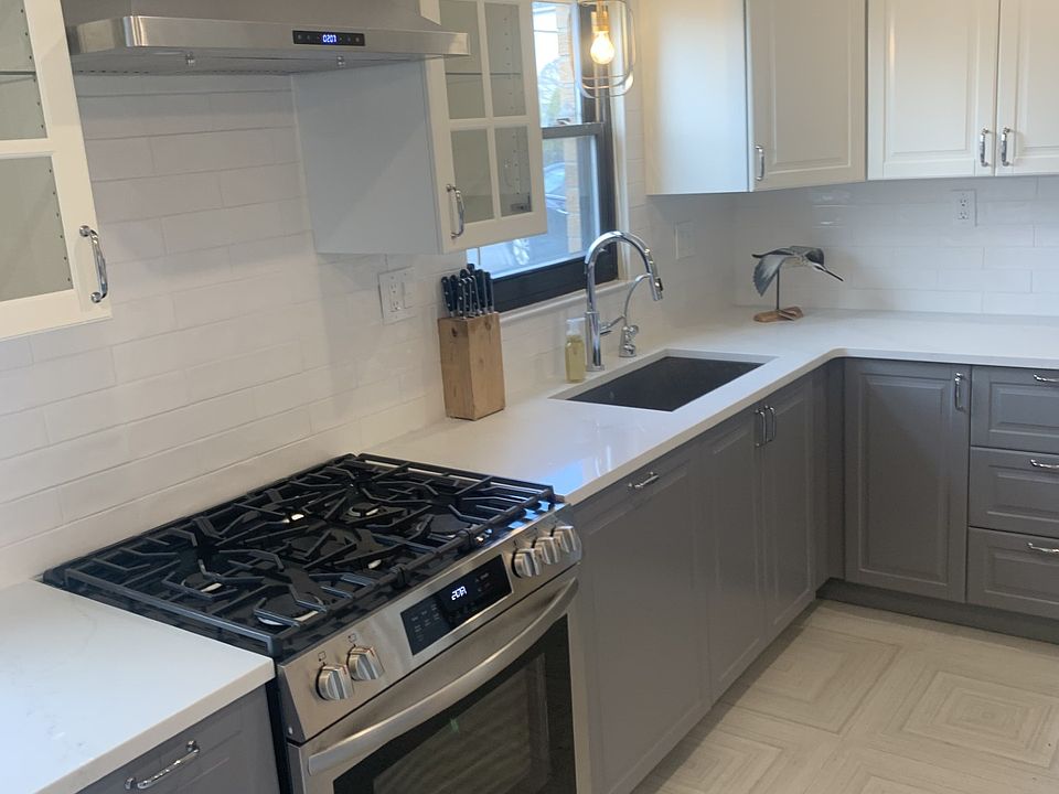 Brand new designer kitchen with high end appliances, filtered drinking water system, microwave drawer, quartz countertops, icemaker, panel-front dishwasher (hidden next to stove), tile floors, garbage disposal.