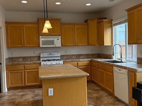 Tile floor kitchen with granite island and tile floor and counter top, built-in microwave and dishwasher, a large pantry