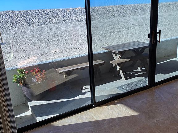 patio with large sliding glass doors and screen doors. during the winter months the city of seal beach creates a large sand mound in front of this strand of the beach. it comes down in the spring.