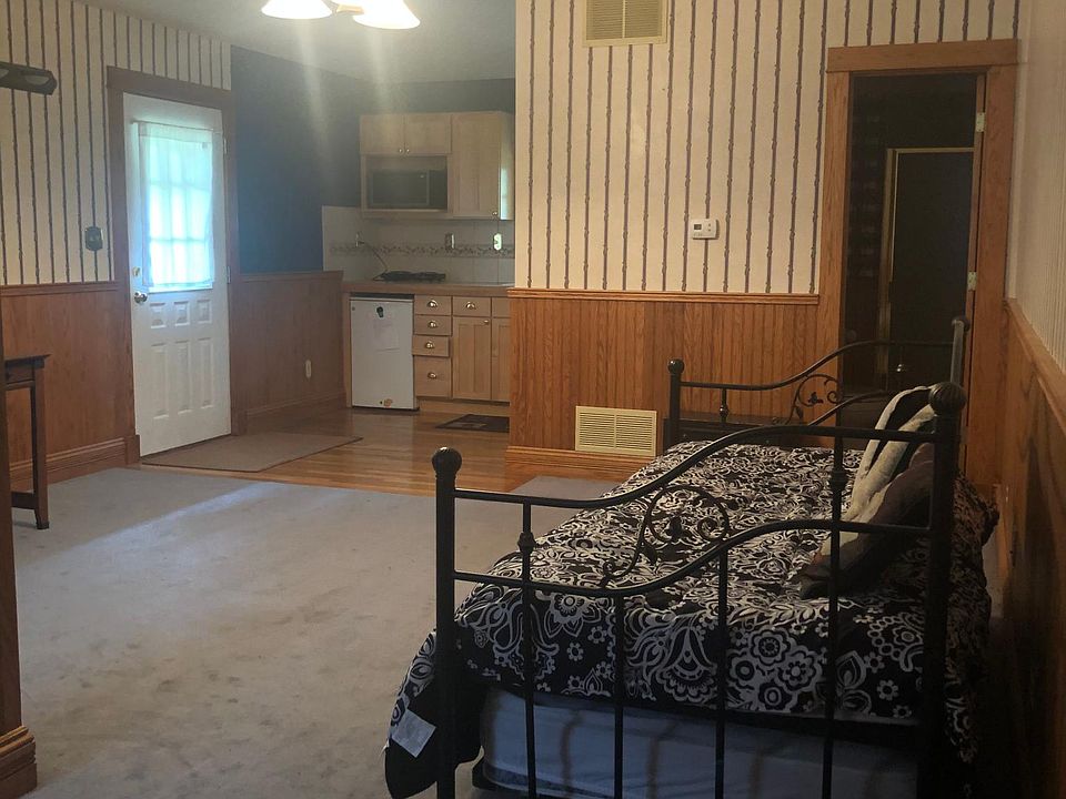 Living area with front main door, kitchen area and entrance to the bathroom. Facing west.