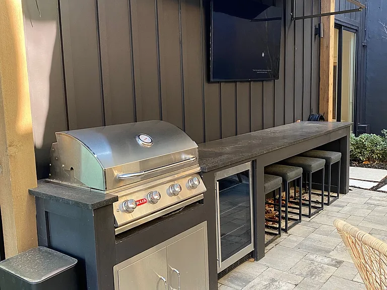 Patio with Grill, refrigerator and seated bar for snacking, and outdoor TV.