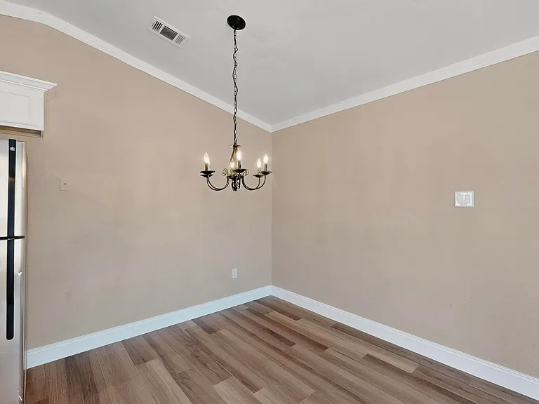 Unfurnished room featuring ornamental molding, light wood finished floors, and a chandelier
