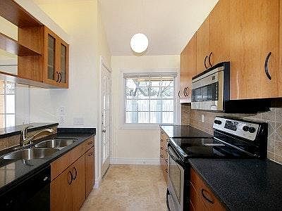 Full service gallery kitchen with natural lighting. Stainless steel appliances.