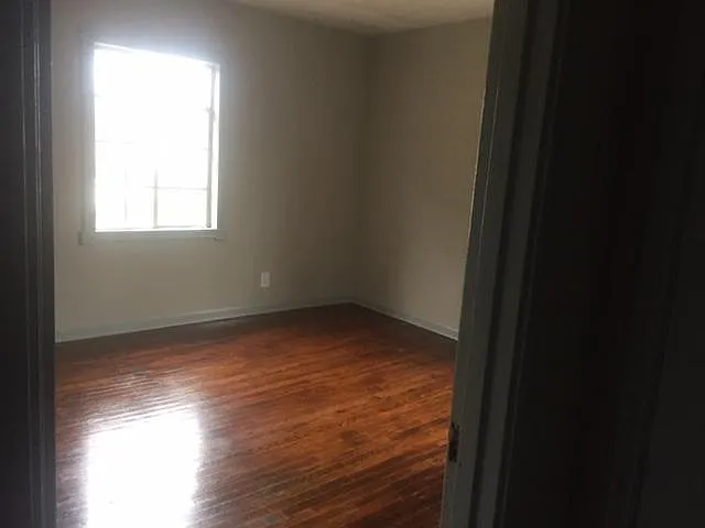 One of two large bedrooms with hardwood floors and plaster walls.