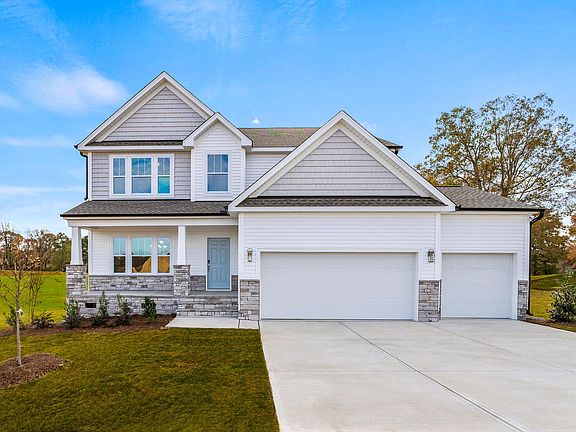 A large white house with a concrete driveway in front of it.