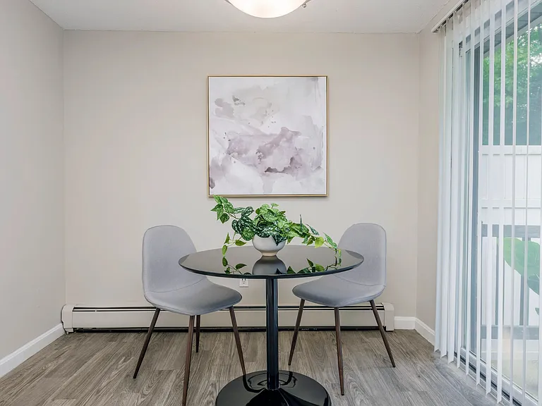 Elegant dining area in The Sycamore floor plans, providing a stylish space for meals next to sliding patio doors and a cozy baseboard heaters.