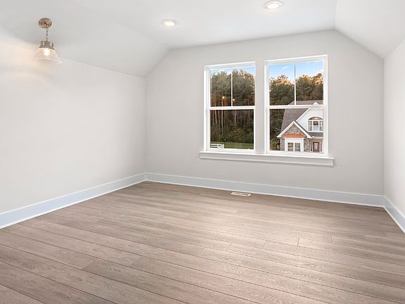 Upper bonus room with large double window, wood floors and vaulted ceiling in a DRB Homes Latitude h