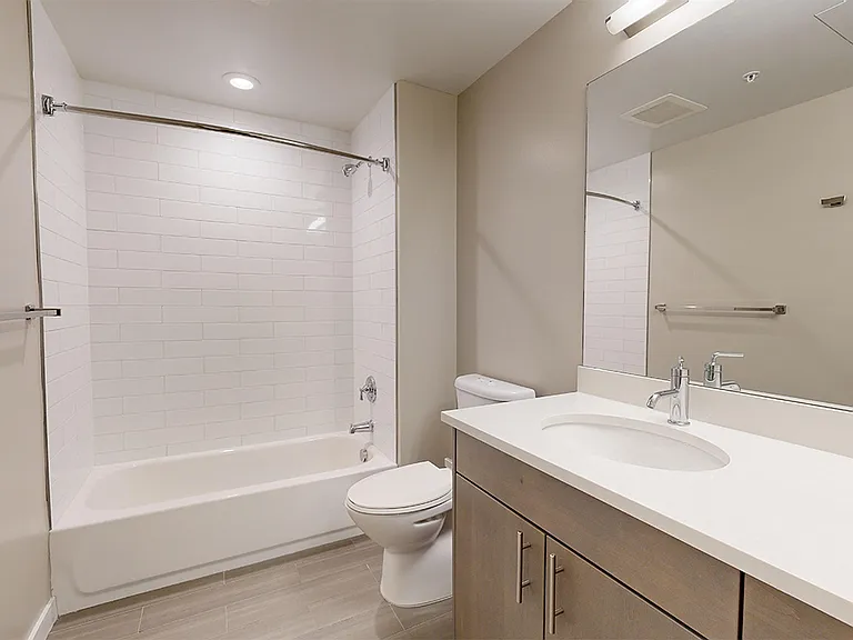 Apartment bathroom with wood-style flooring.