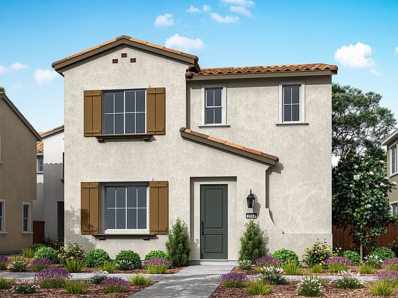 A two-story Mediterranean-style house with a tiled roof, surrounded by a well-landscaped garden feat