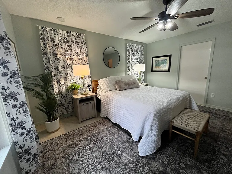 Primary bedroom with bench, full length mirror, TV, view into private backyard, USB ports in nightstands