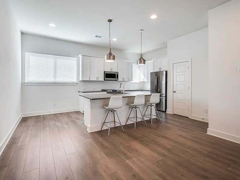 Kitchen with bar and pendant lights. Pantry is on the right.