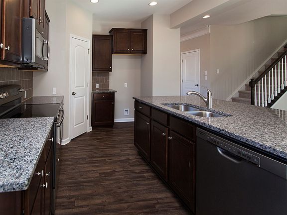 Kitchen hosts oversized island, granite countertops, tile backsplash, stainless steel appliances and